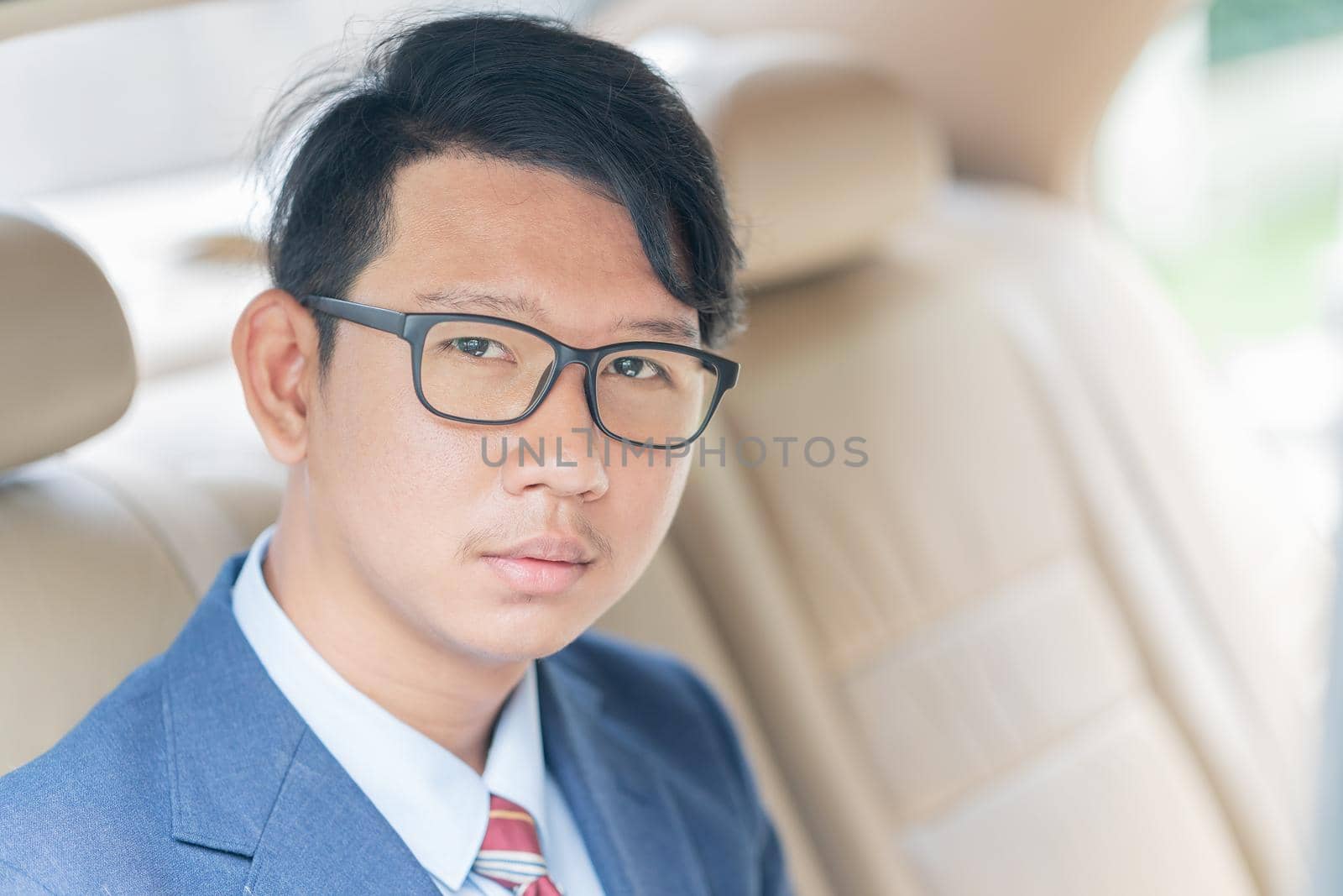 Young asian business men portrait in suit sit in the backseat of a car