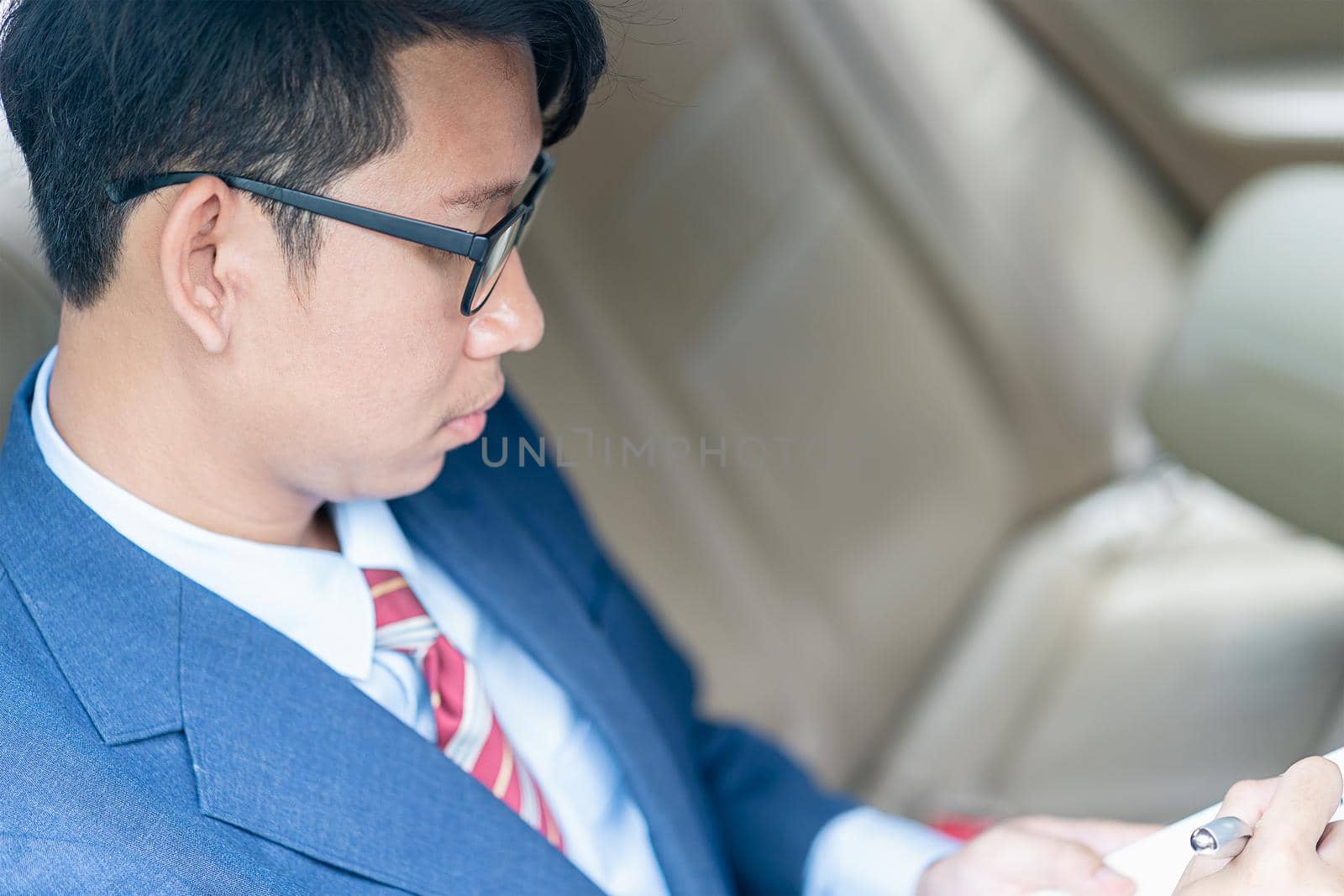 Businessman working in the backseat of a car  by stoonn