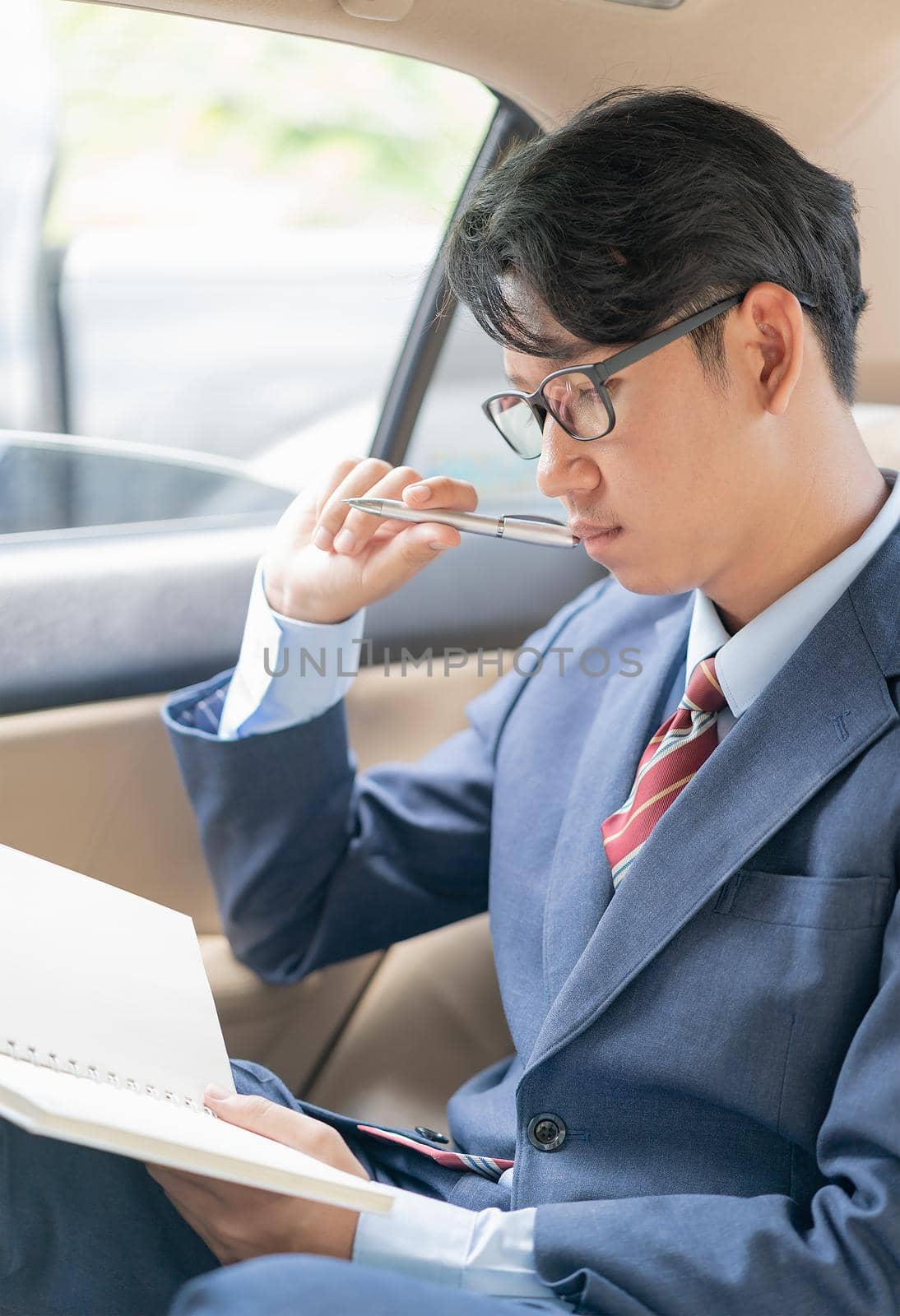 Young asian business men portrait in suit working in the backseat of a car