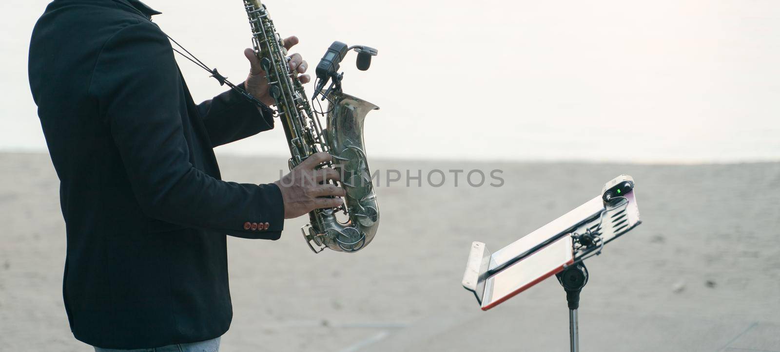 Musician man playing saxophone on the beach.