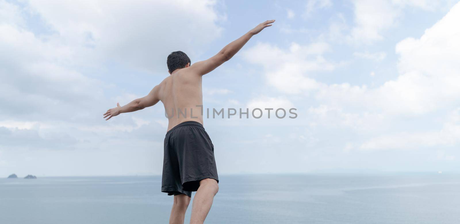 Back view of man opened hands with delight at the ocean and sky. by sirawit99