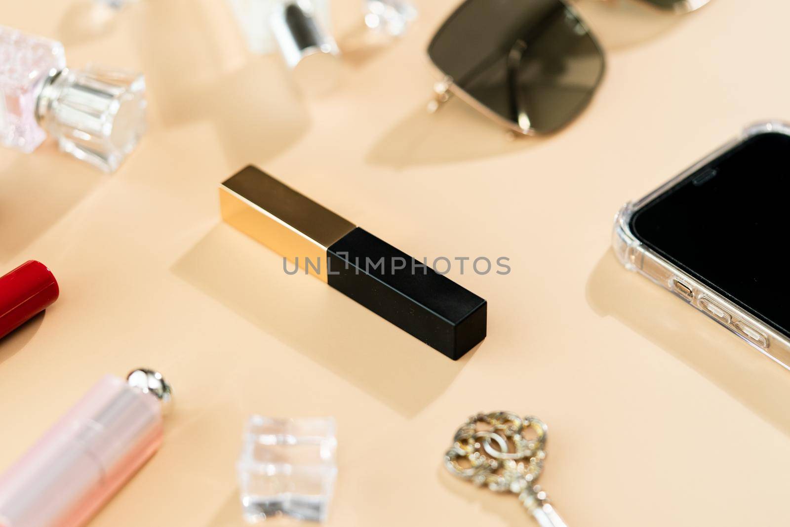 woman table desk frame. cosmetics, lipstick, perfume, phone and sunglasses on yellow background.