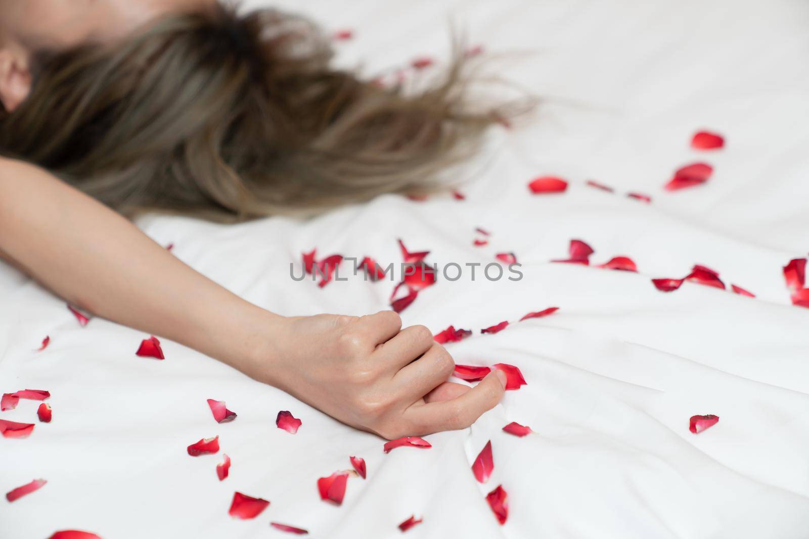 Women hand pulling or grasping white sheets. Hand sign orgasm of woman on white bed sheet with rose petals. by sirawit99