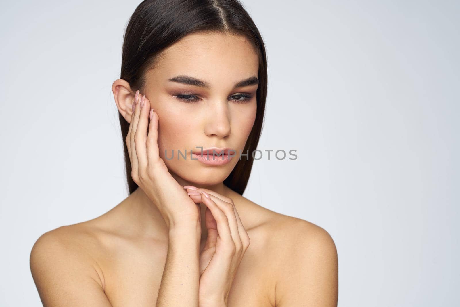 Woman with long hair bared shoulders clean skin body care light background. High quality photo
