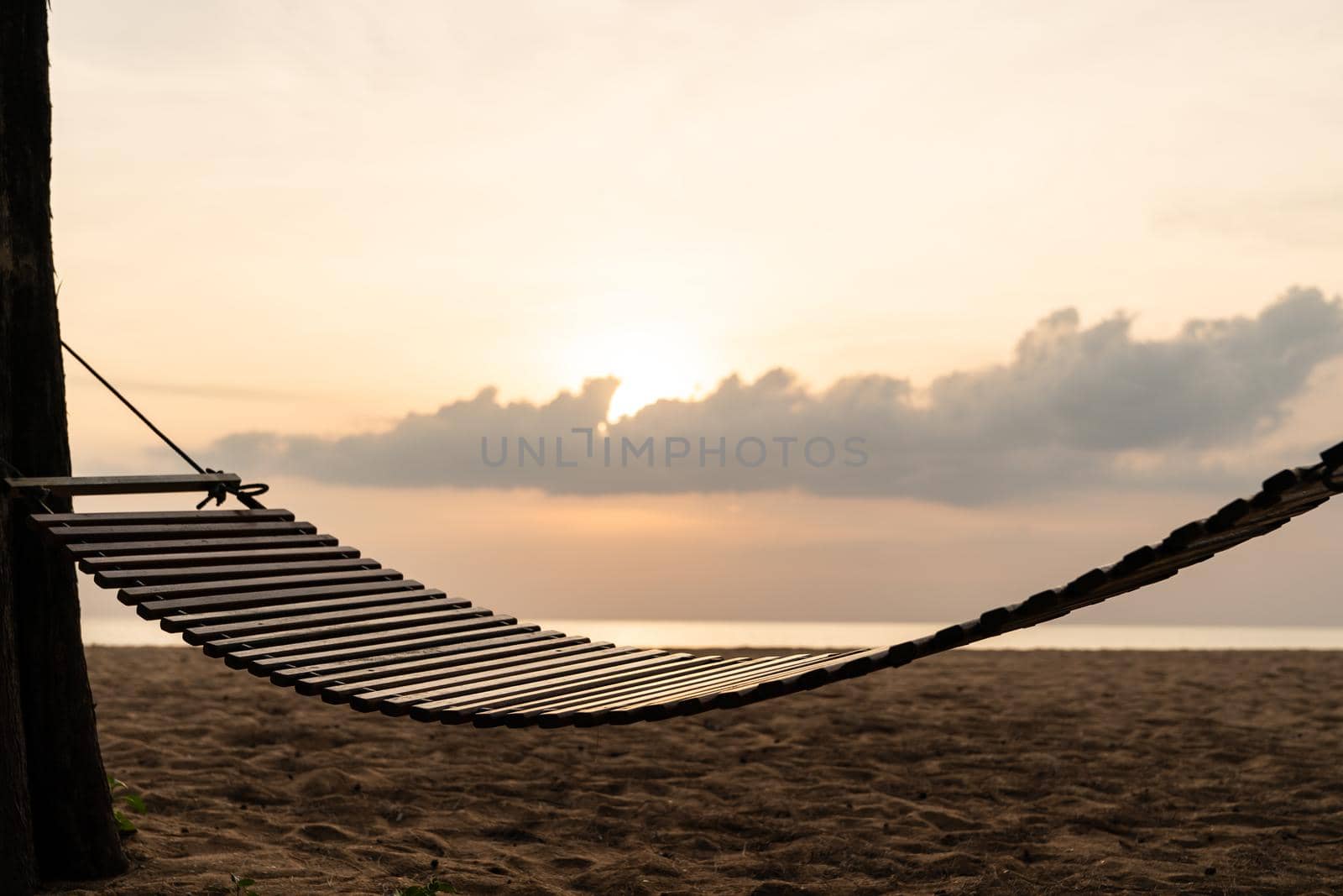 A wooden swing or cradle on the beach with beautiful cloud and sky.