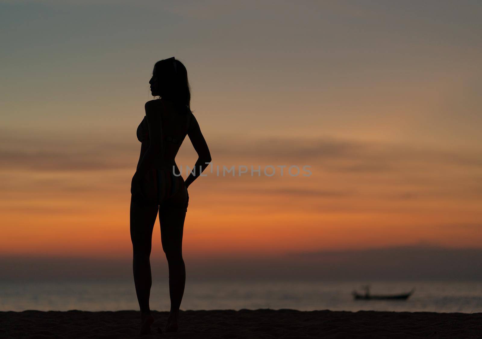 Silhouette portrait of woman wearing bikini on the beach, golden sunset moment. Holiday and travelling concept.