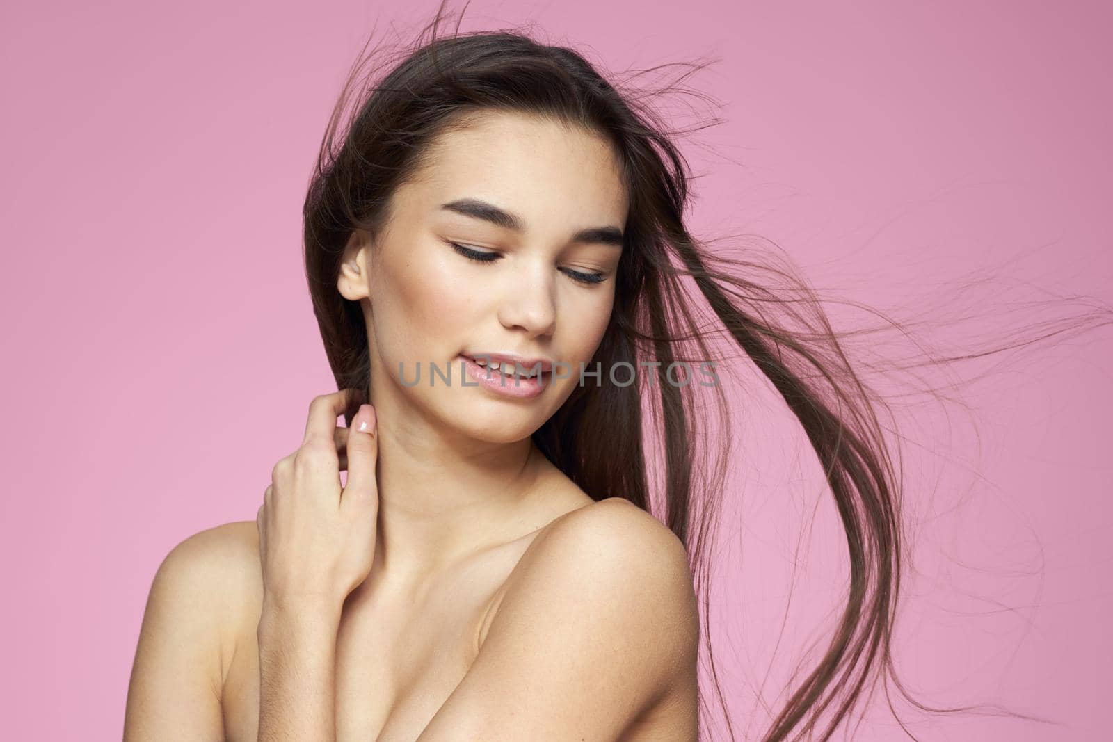 Pretty brunette naked shoulders clear skin pink background. High quality photo