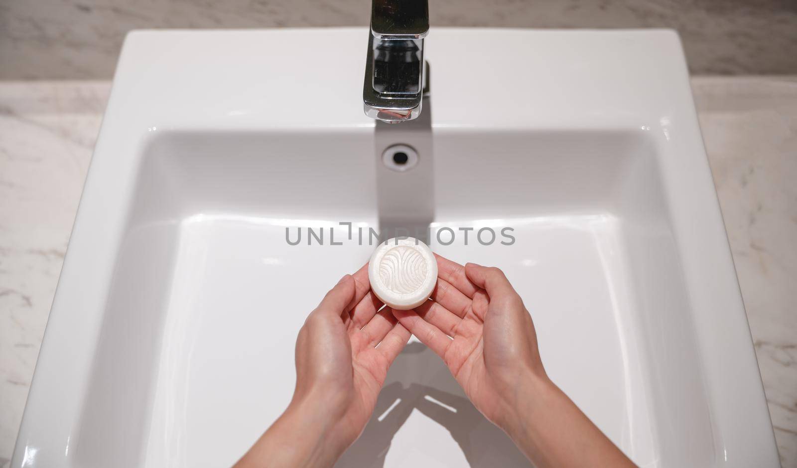 Woman wash hands with soap in the sink with water.