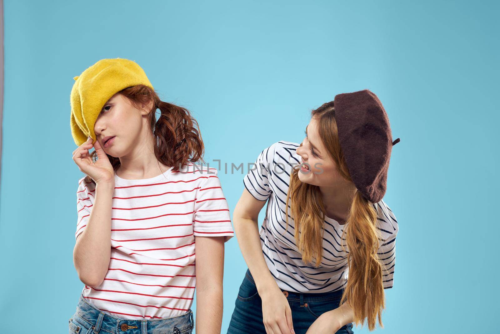 Fashion sisters in hats fun lifestyle blue background studio. High quality photo
