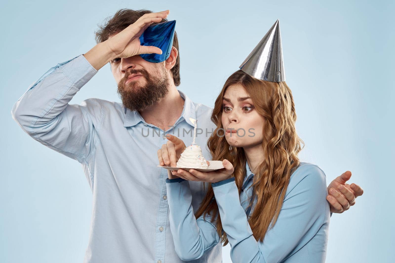 Cheerful man and woman with cake in a plate corporate party blue background. High quality photo