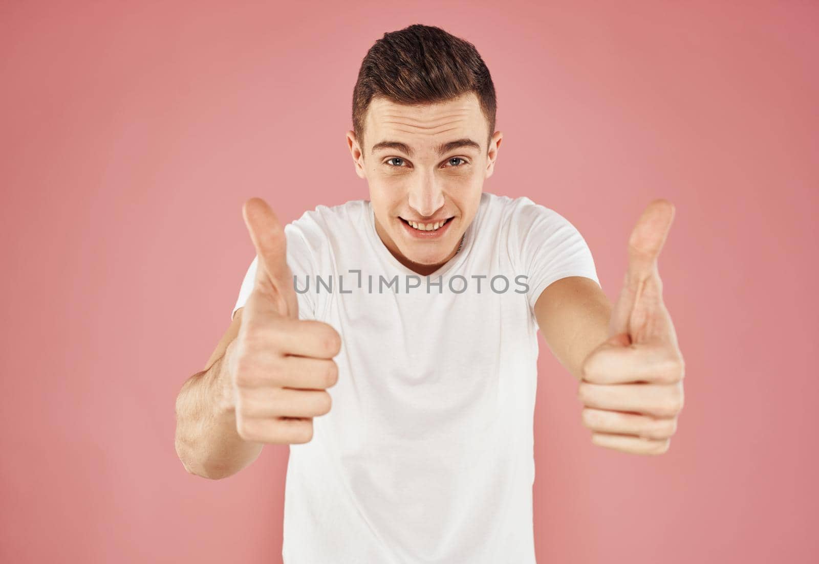 Guy on a pink background gesturing with his hands in a white t-shirt cropped view. High quality photo