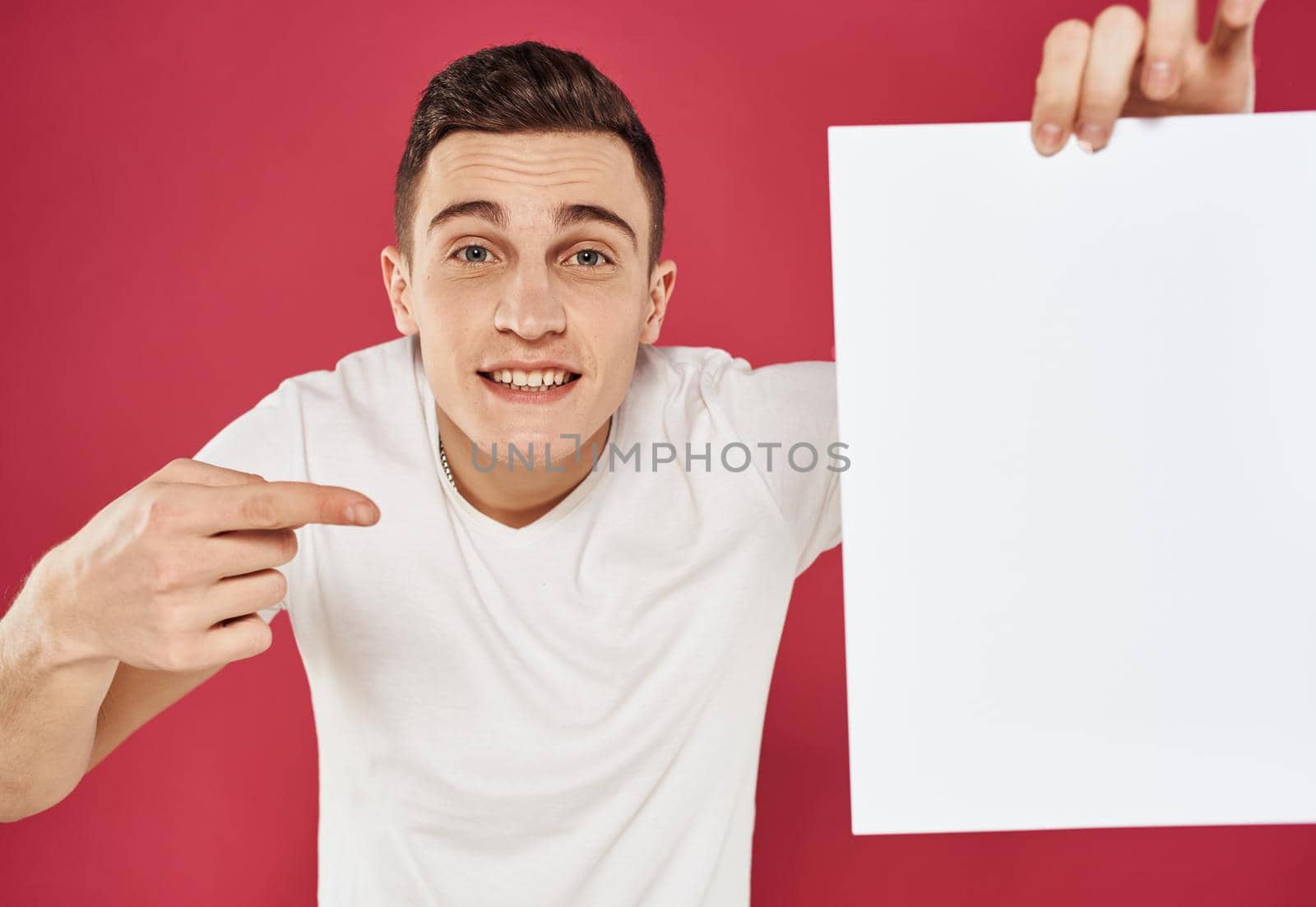 Man with a vertical sheet of paper on a red advertising background. High quality photo