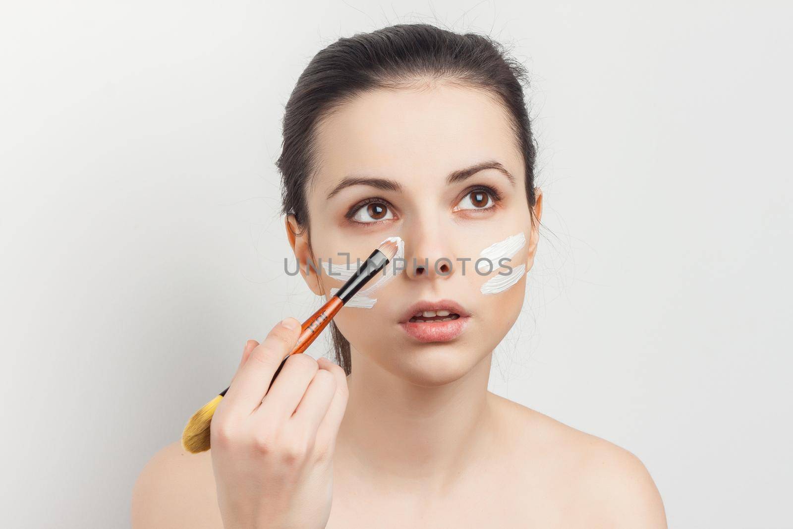 bare-shouldered brunette applying makeup on face cropped view by SHOTPRIME