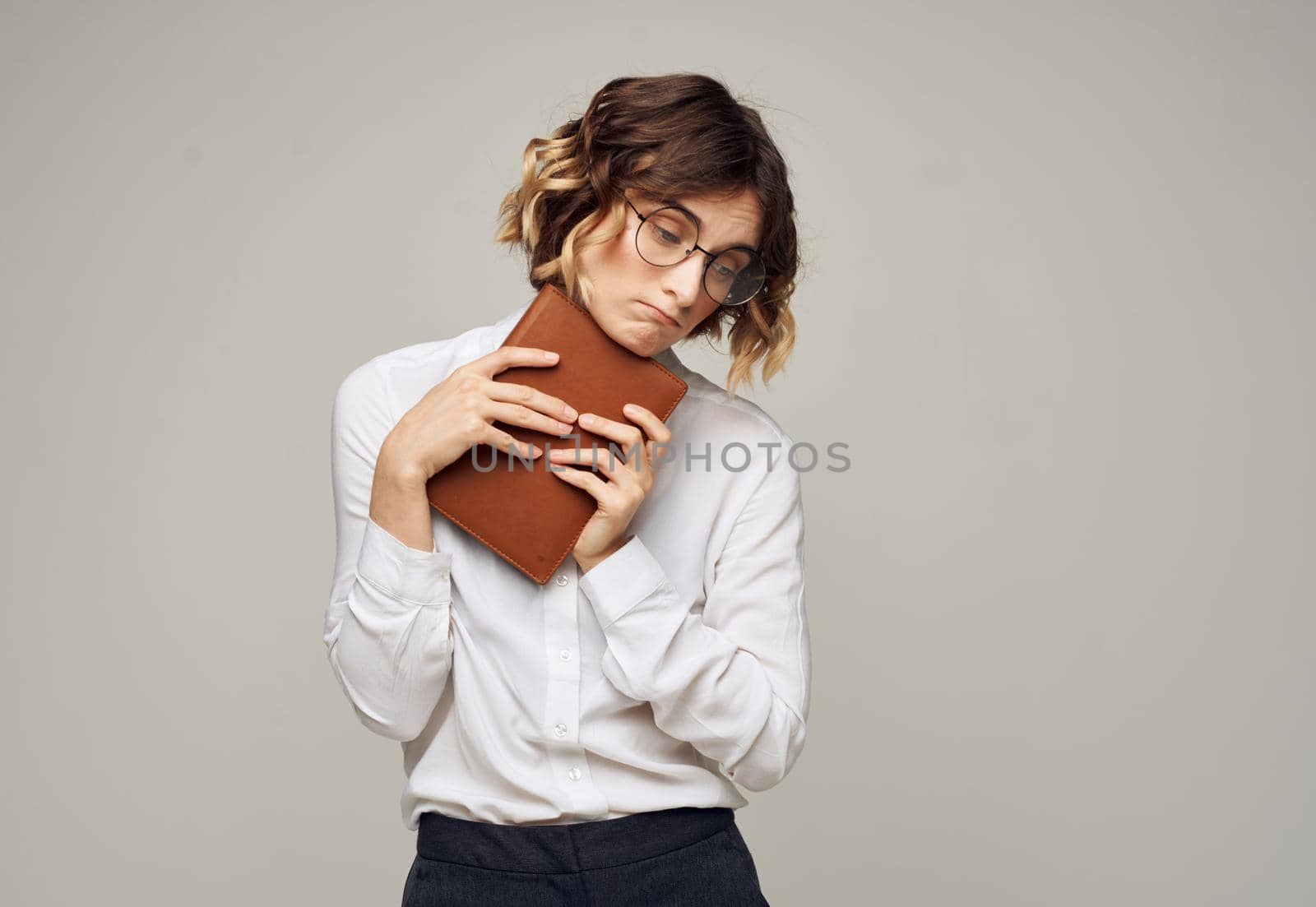 Pretty woman in glasses and a white shirt on a gray background with a book in her hands. High quality photo