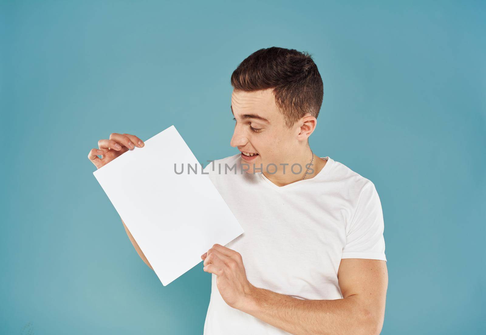 Male advertiser with a white sheet of paper on a blue background mockup Flyer by SHOTPRIME