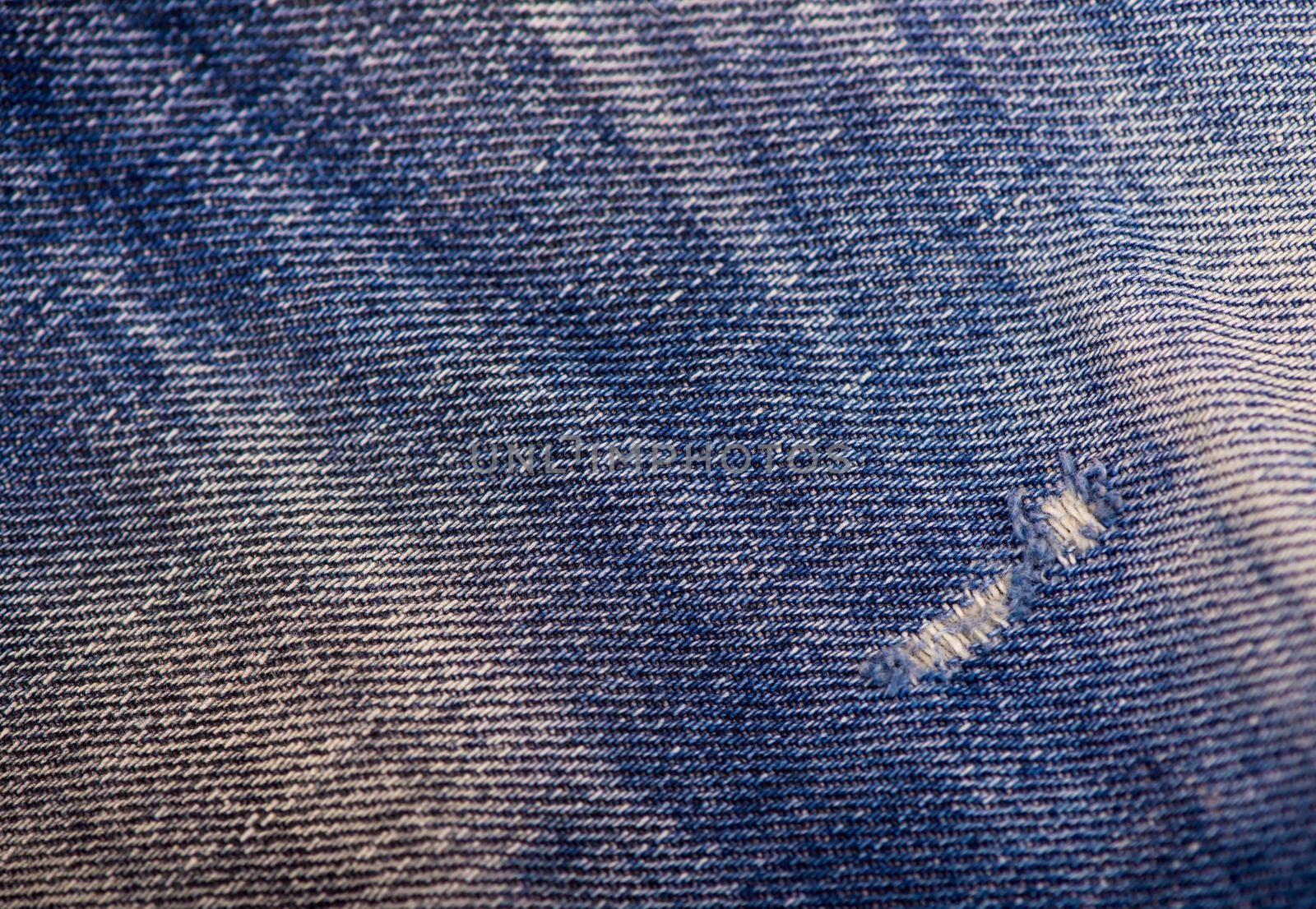 Texture of blue jeans background, ripped jeans.