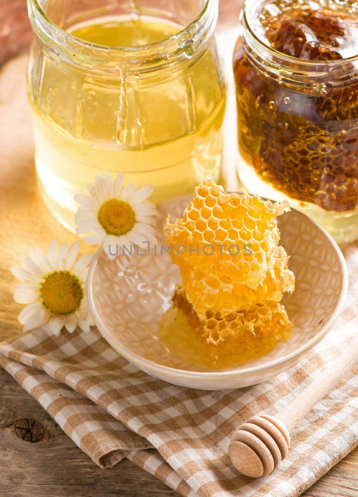 Close up honeycomb with honey in glass jar on wooden board, top view