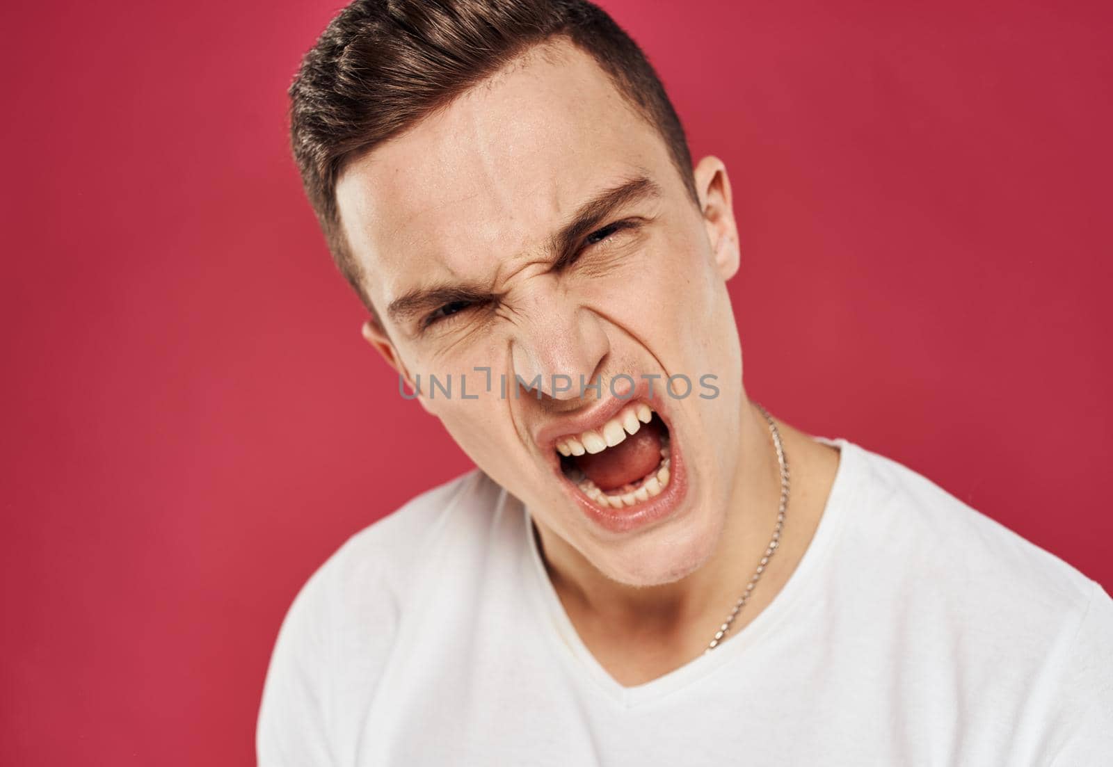 emotional man in white t-shirt studio dissatisfaction red background by SHOTPRIME