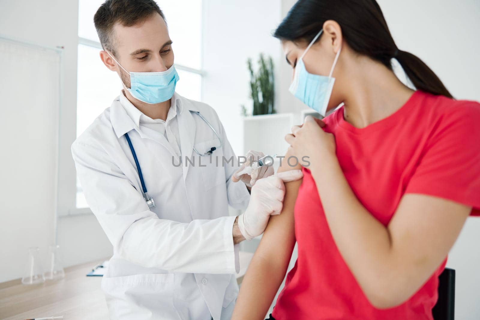 male doctor in white coat treats here before patient injection covid vaccination by SHOTPRIME