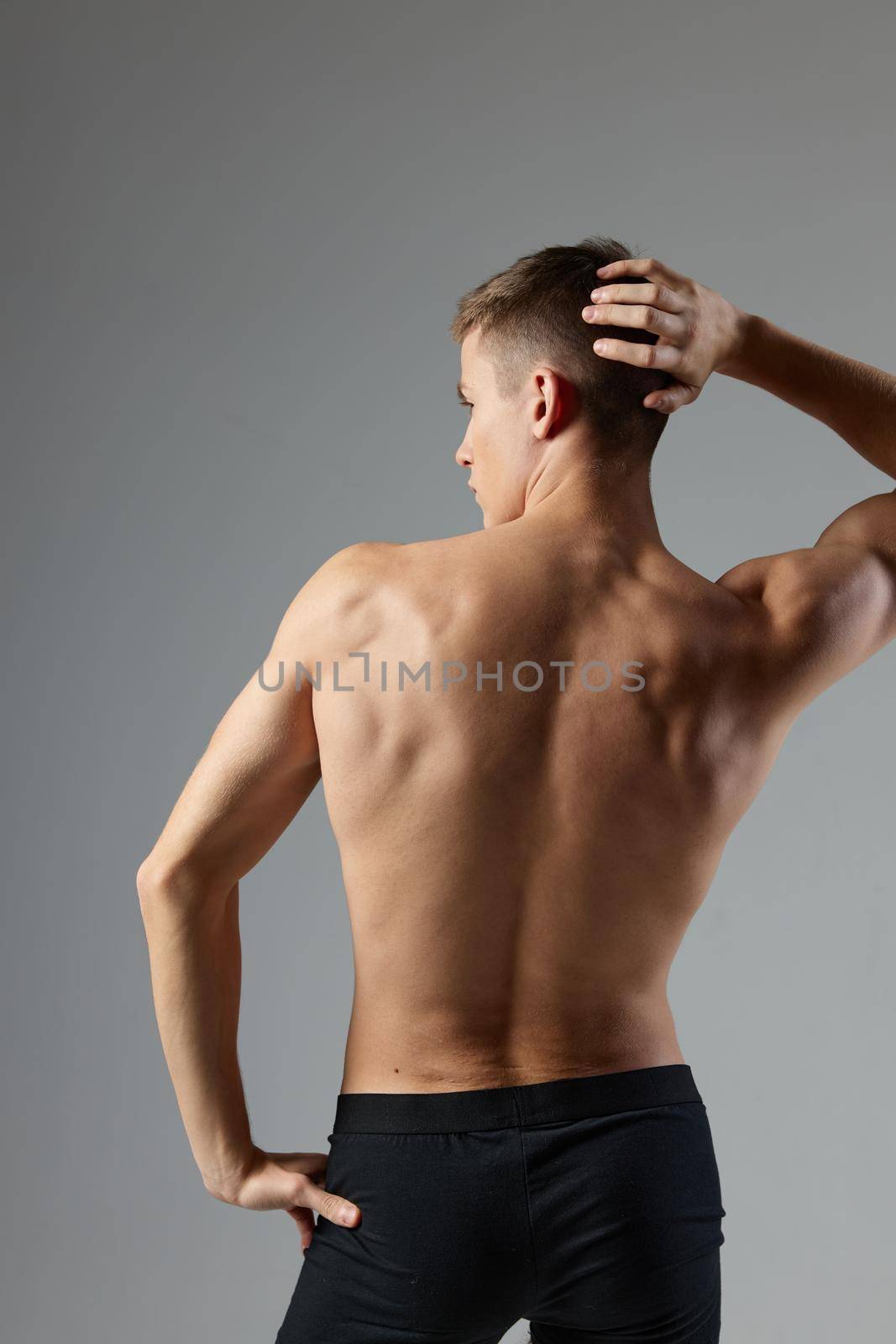 athletic male athlete posing with pumped body back view isolated background by SHOTPRIME