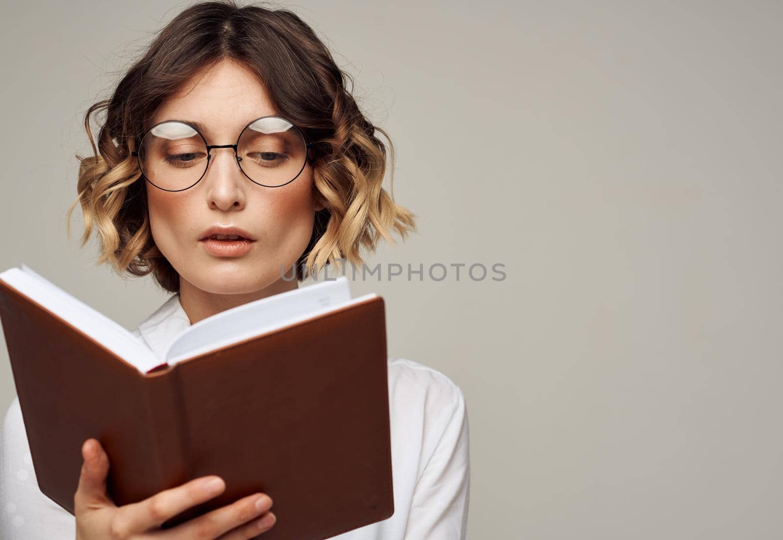 Woman with a notepad in her hands and wearing glasses on a gray background cropped view of a Light shirt by SHOTPRIME