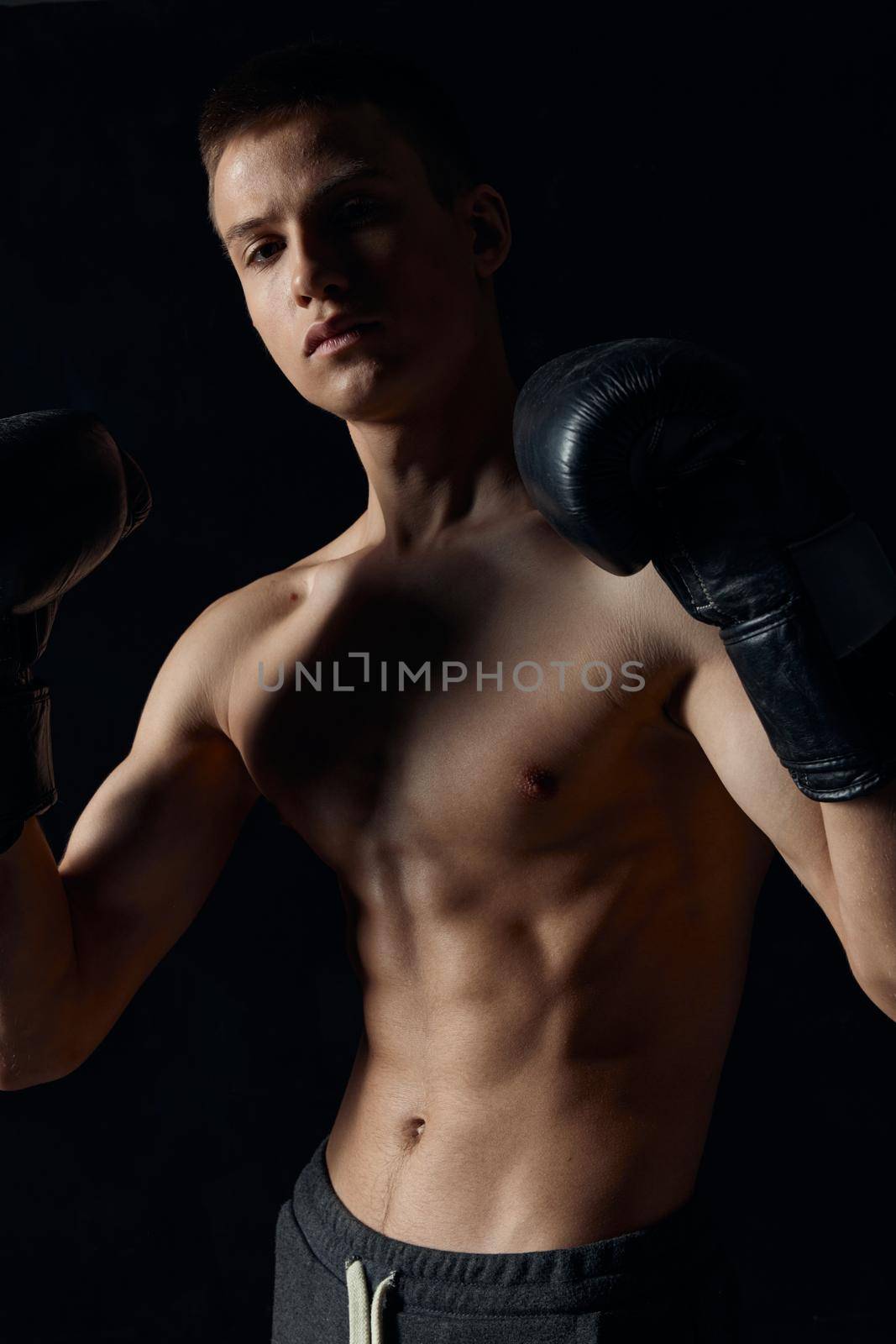 boxer in black gloves on a dark background inflated torso bodybuilder . High quality photo