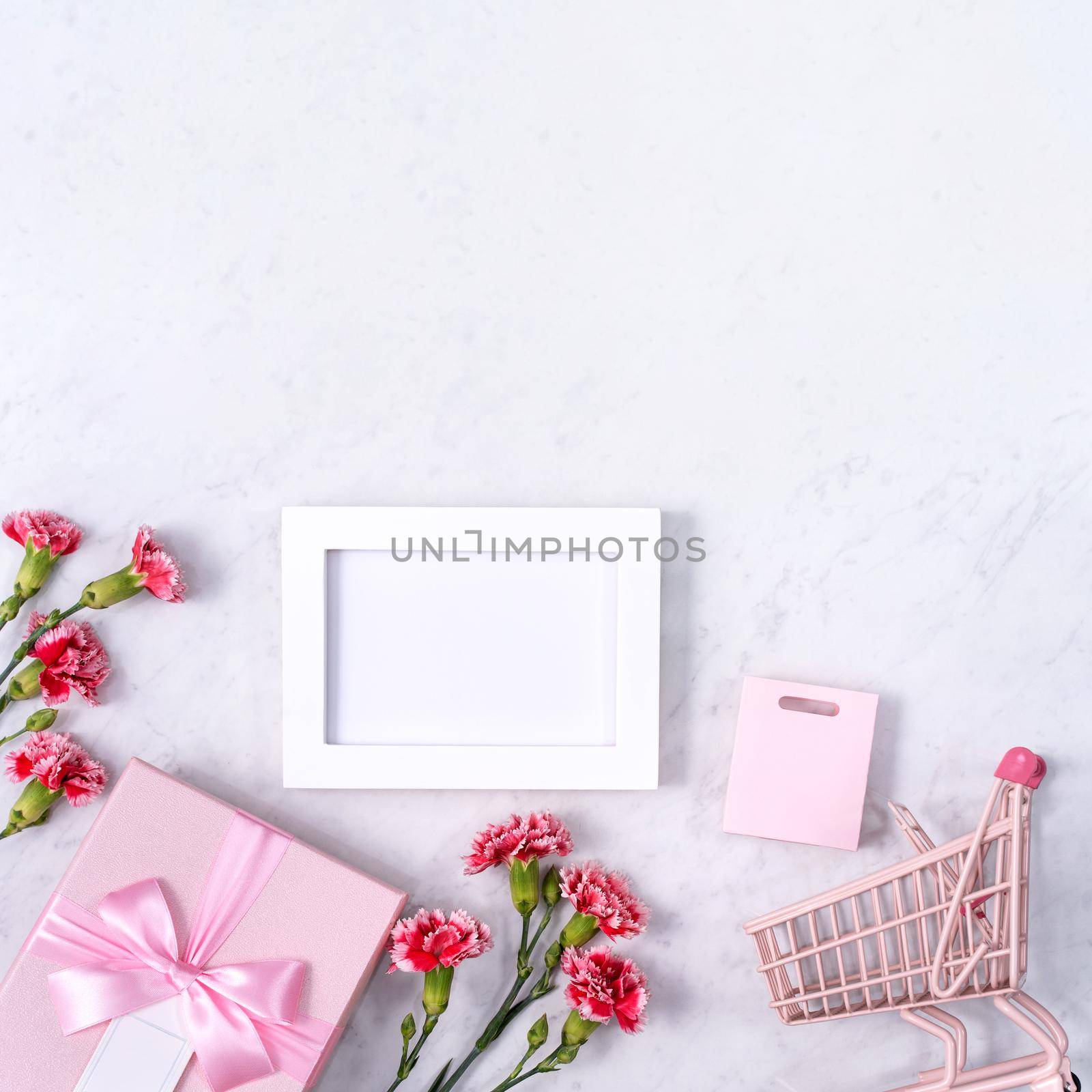 Concept of Mother's day holiday greeting design with carnation bouquet and gift on white marble background