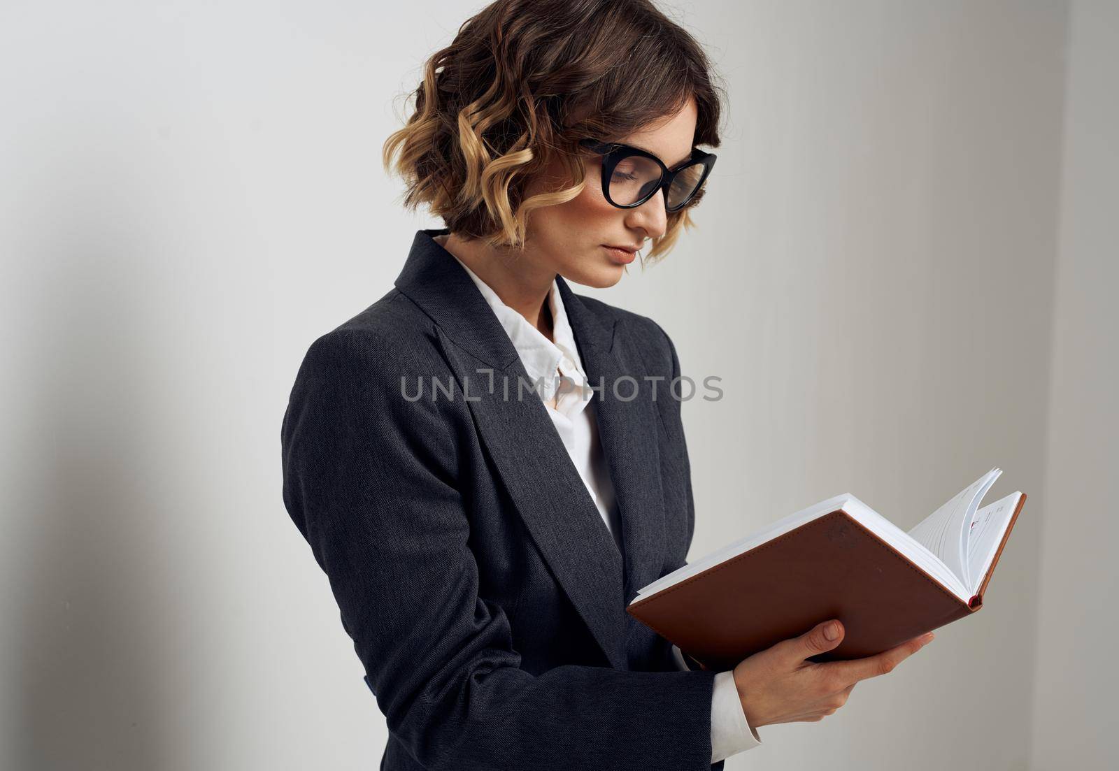 Business woman with book in glasses hands on face of classic suit. High quality photo