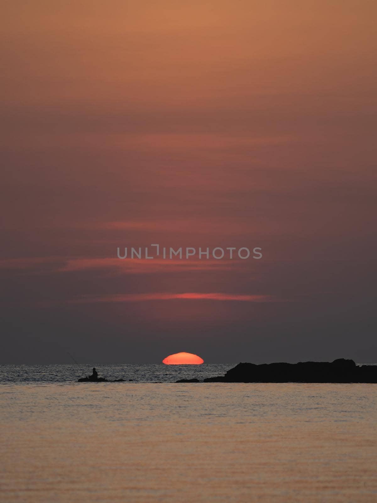 Sunset ocean view. Sun above the sea on orange sky.