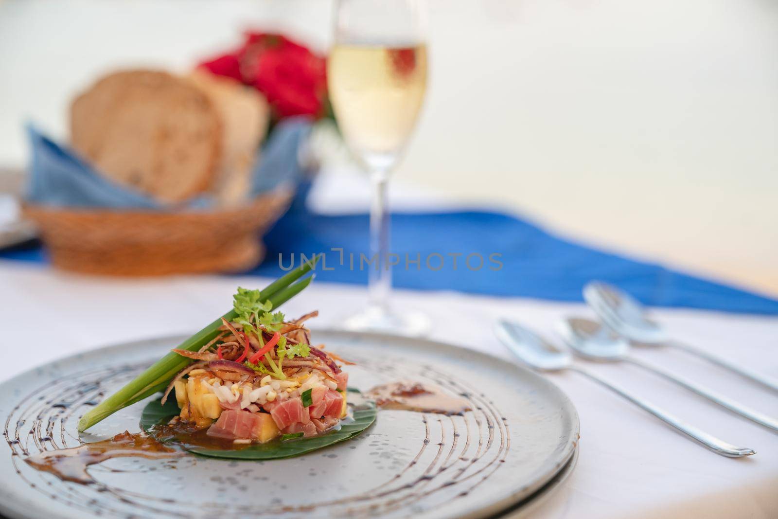 Dish of tuna salad on dining table with champagne for dinner at restaurant.