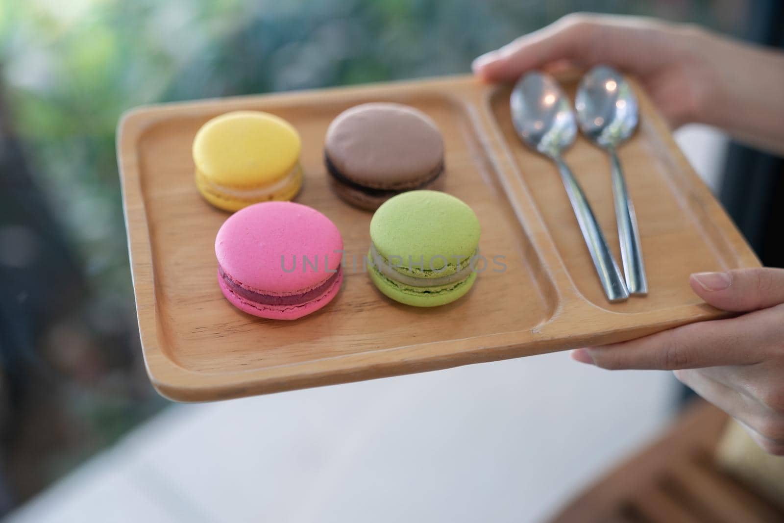 Colorful macaroons and spoon of coffee on a wooden tray. by sirawit99