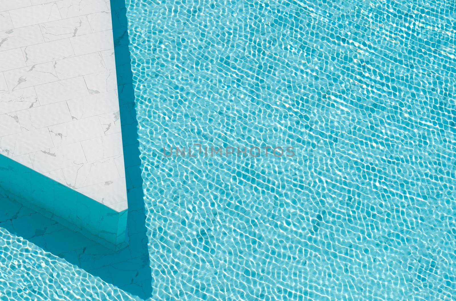 Blue ripped water in swimming pool made from white marble stone tile.