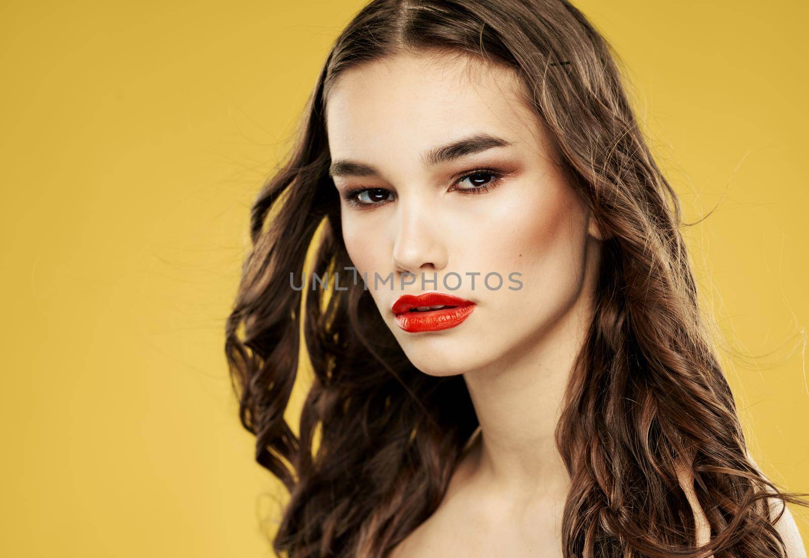 Beautiful brunette with red lips eyeshadow and yellow background. High quality photo