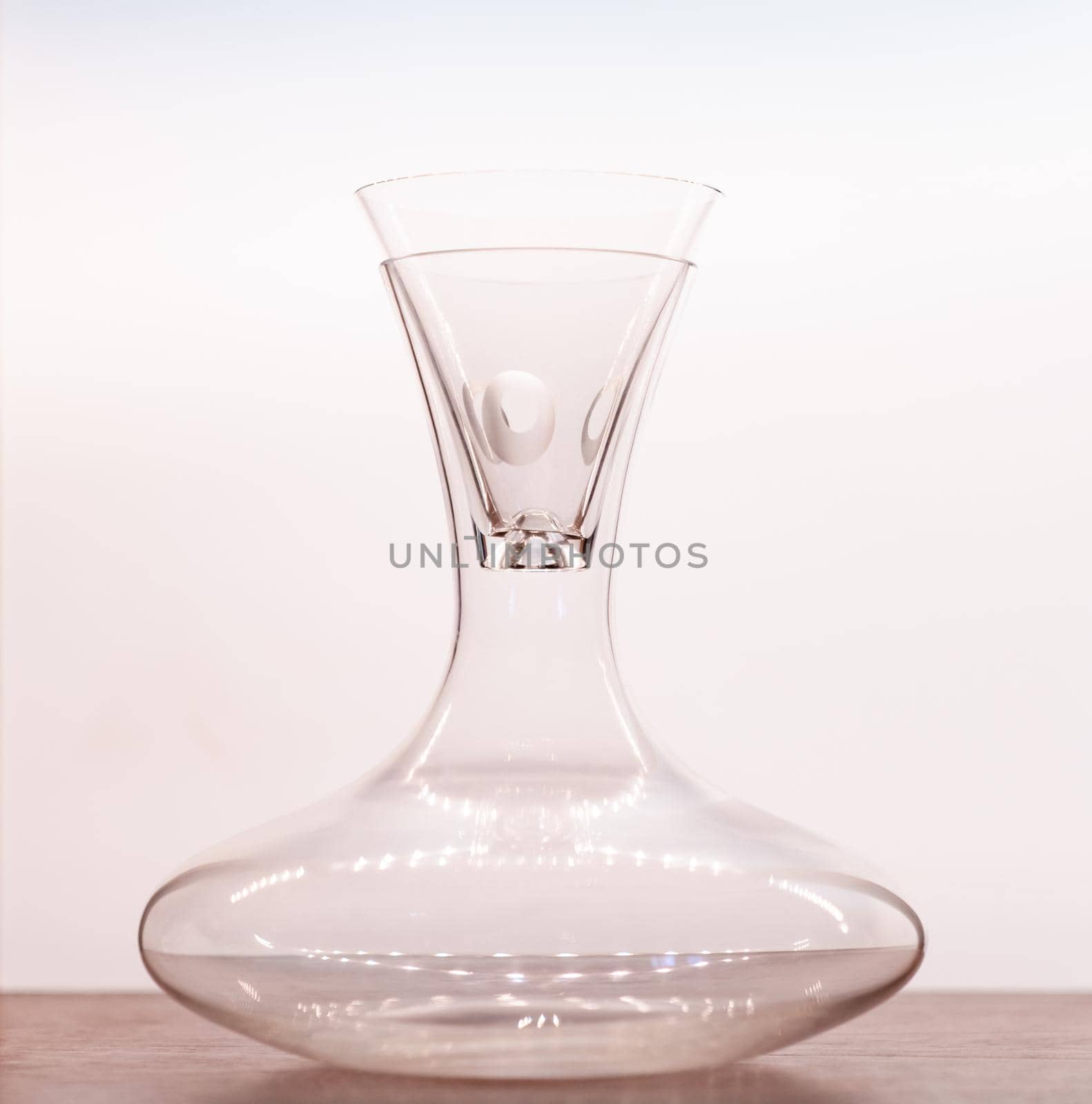 Transparent pitcher with glass on wood table with white background.