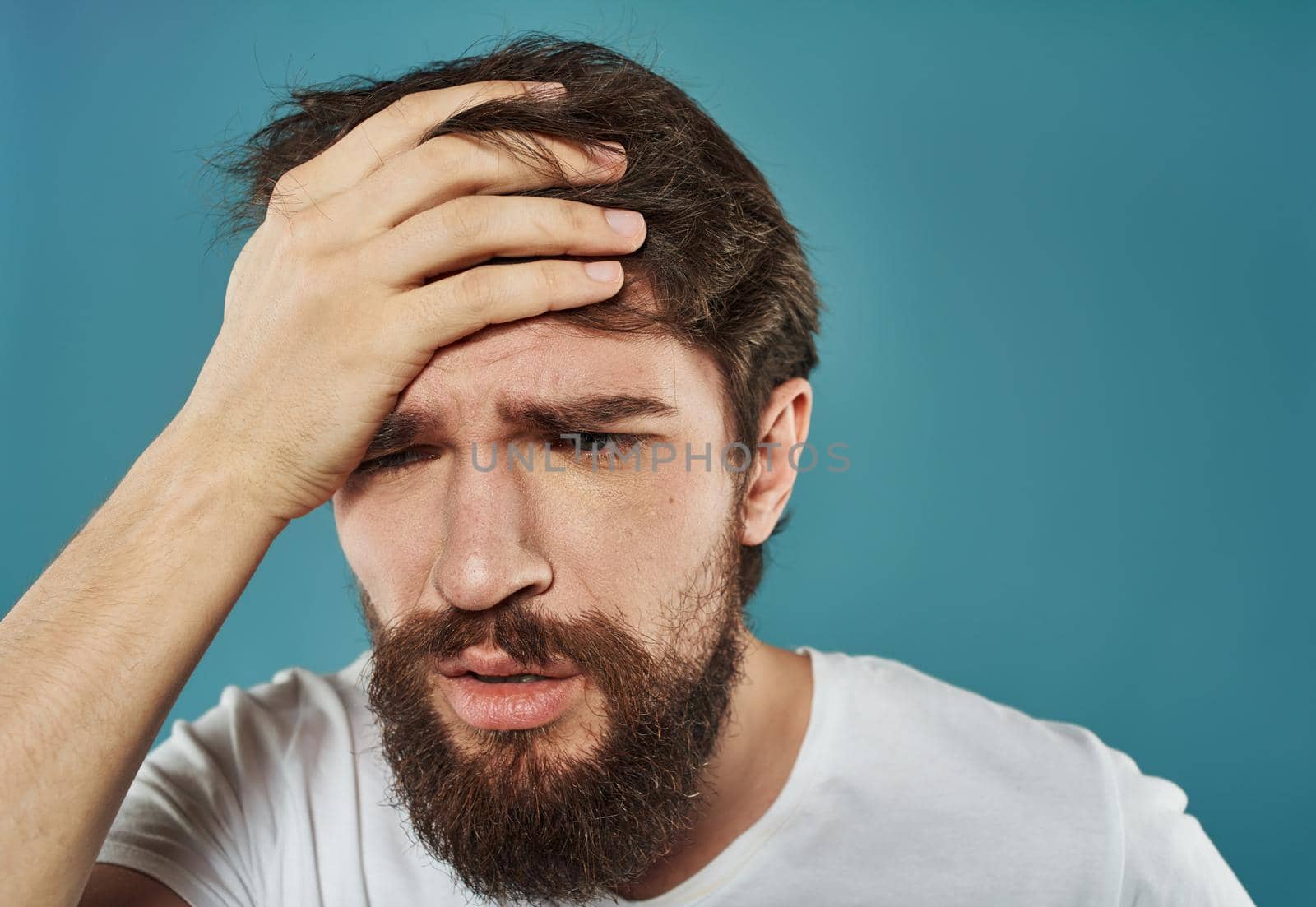 A man on a blue background is touching his head with his hands by SHOTPRIME