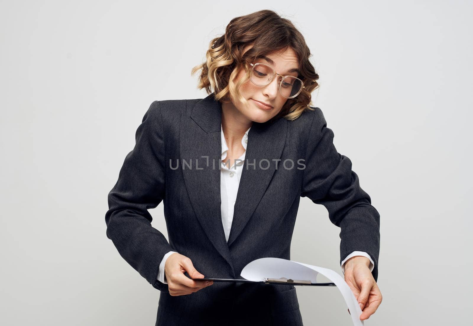 A woman with documents in a folder on a light background gestures with her hands by SHOTPRIME