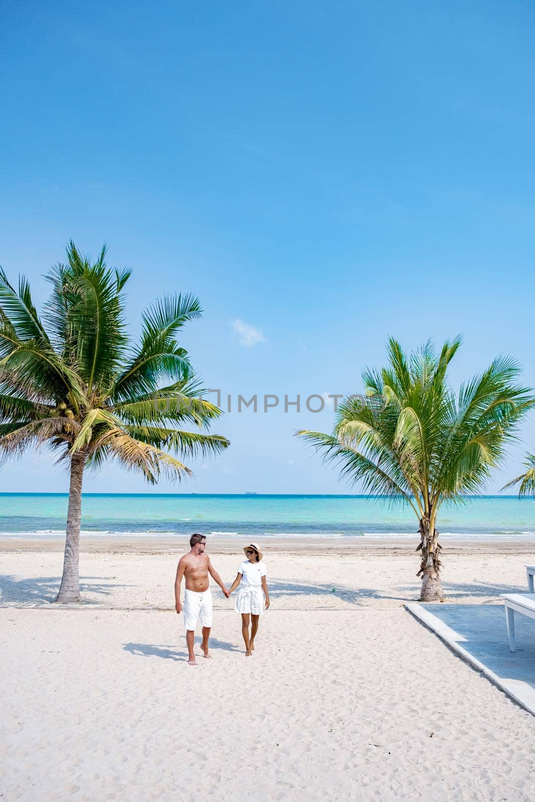 couple on vacation in Thailand, Chumpon province, white tropical beach with palm trees, Wua Laen beach Chumphon area Thailand, palm tree hanging over the beach with a couple on vacation in Thailand.