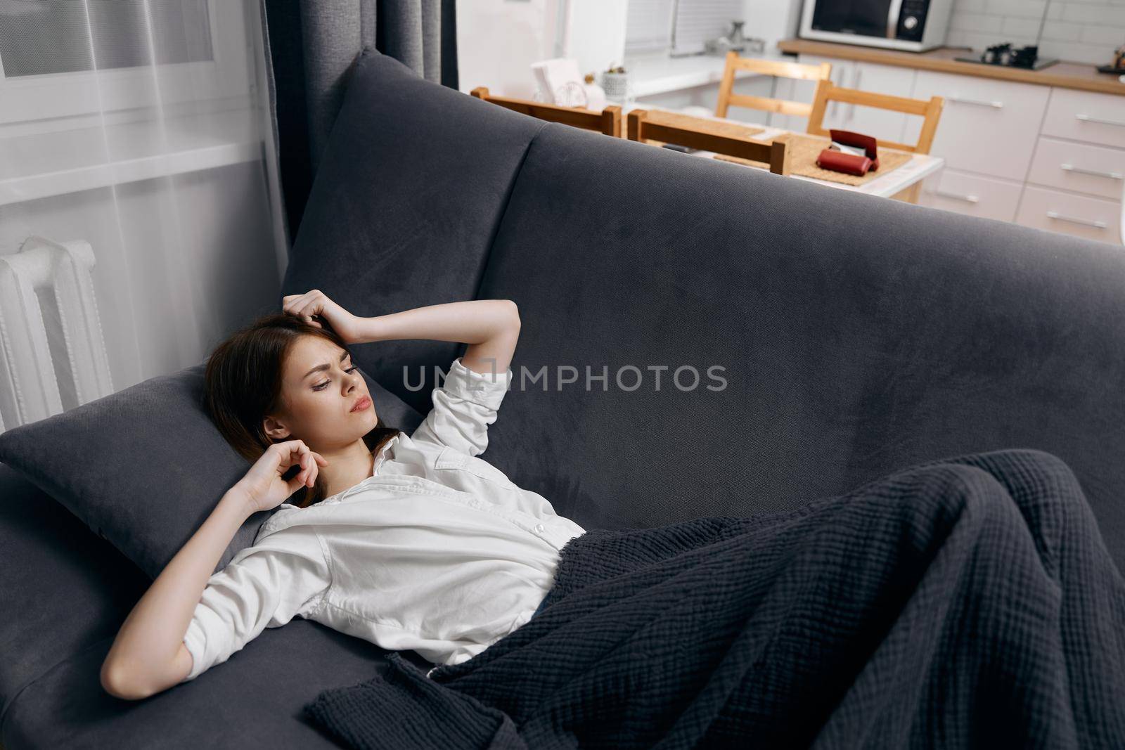 a woman in a white t-shirt lies on the sofa under a blanket and gestures with her hands by SHOTPRIME