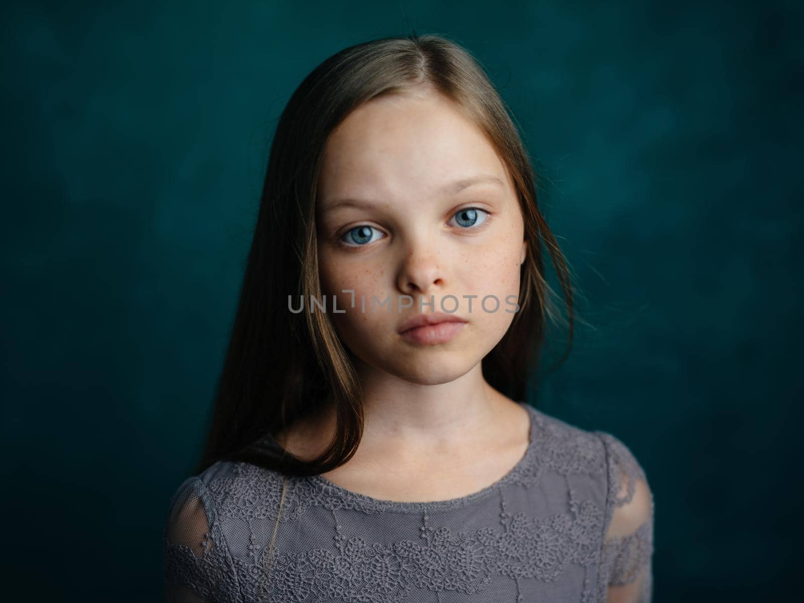 Cute blue-eyed girl in a gray dress on a green background cropped view by SHOTPRIME