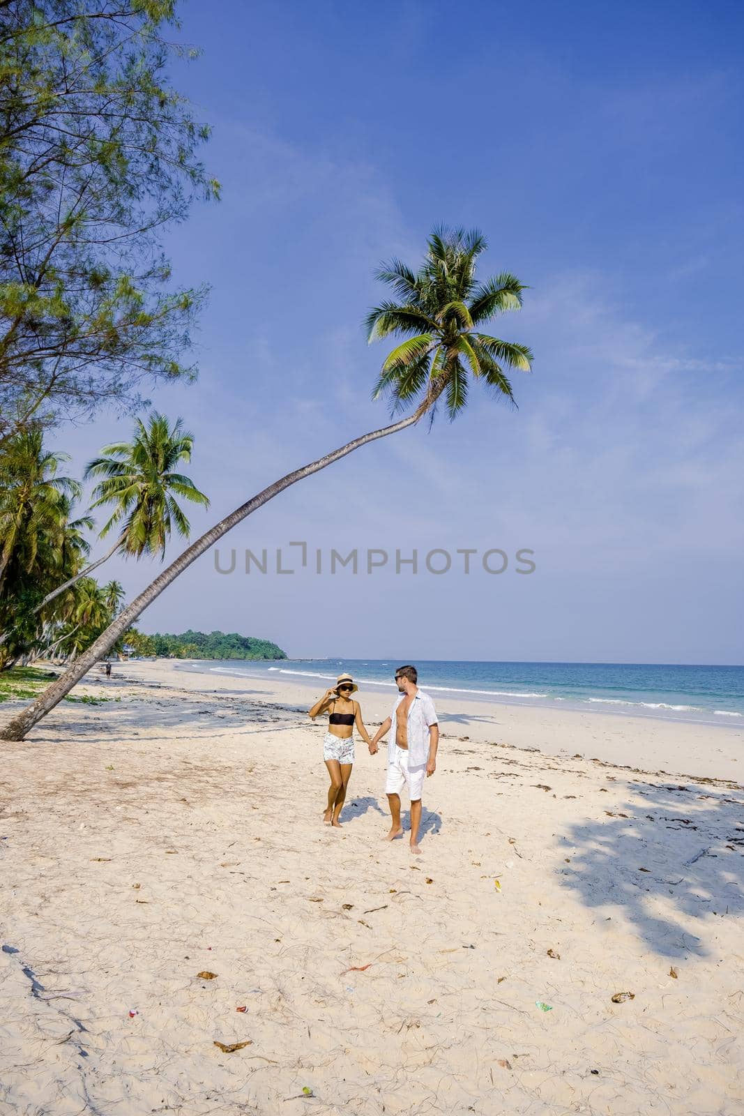 couple on vacation in Thailand, Chumpon province, white tropical beach with palm trees, Wua Laen beach Chumphon area Thailand, palm tree hanging over the beach with a couple on vacation in Thailand.