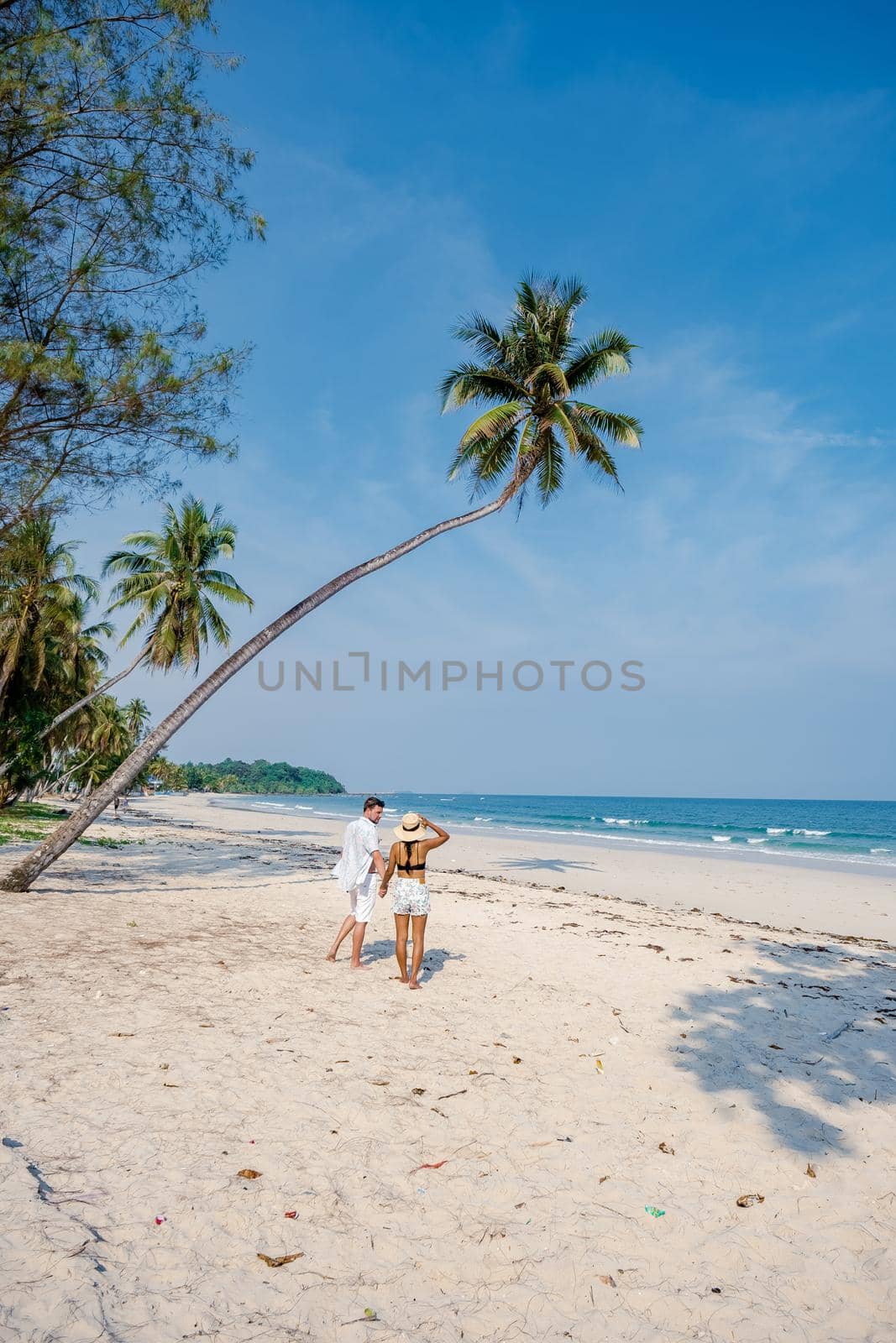 couple on vacation in Thailand, Chumpon province, white tropical beach with palm trees, Wua Laen beach Chumphon area Thailand, palm tree hanging over the beach with a couple on vacation in Thailand.