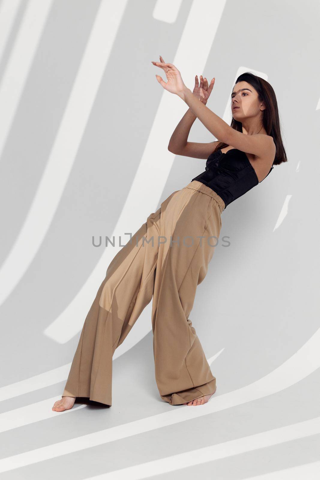 attractive woman in beige pants and black top gestures with her hands. High quality photo