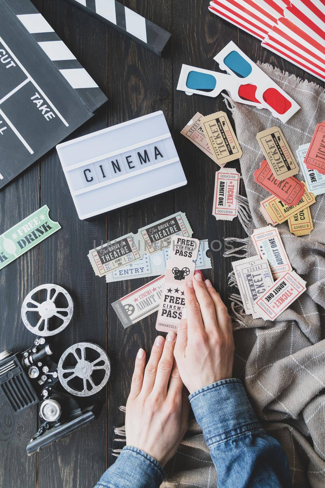 Retro and vintage. Old school film reel projector, lightbox with word Cinema, clapper board. Woman hands holding vintage movie tickets