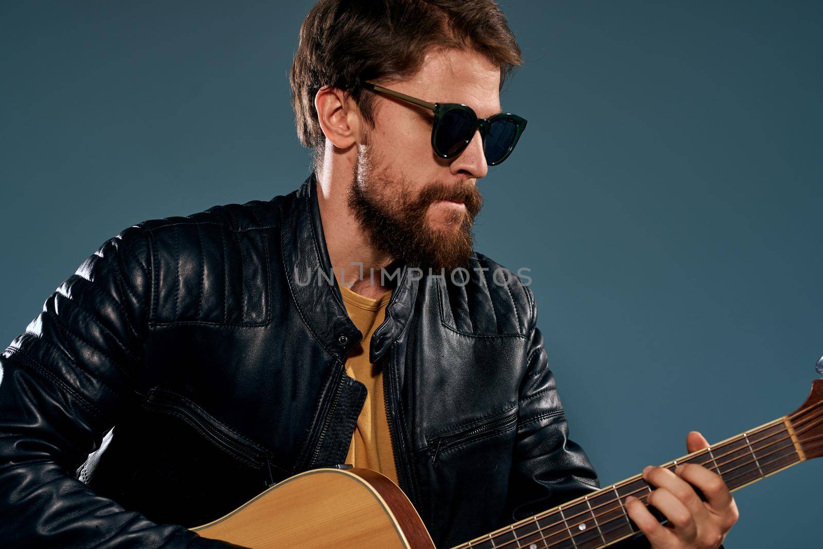Male musician in leather jacket performed by musical group guitar. High quality photo