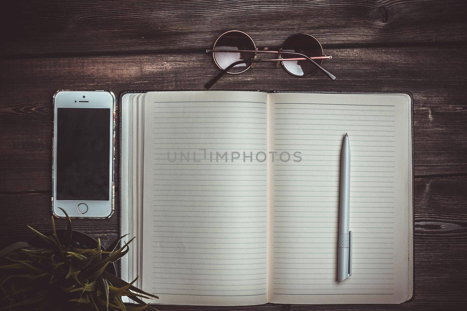 open notepad lies on a wooden table and pen glasses mobile phone. High quality photo
