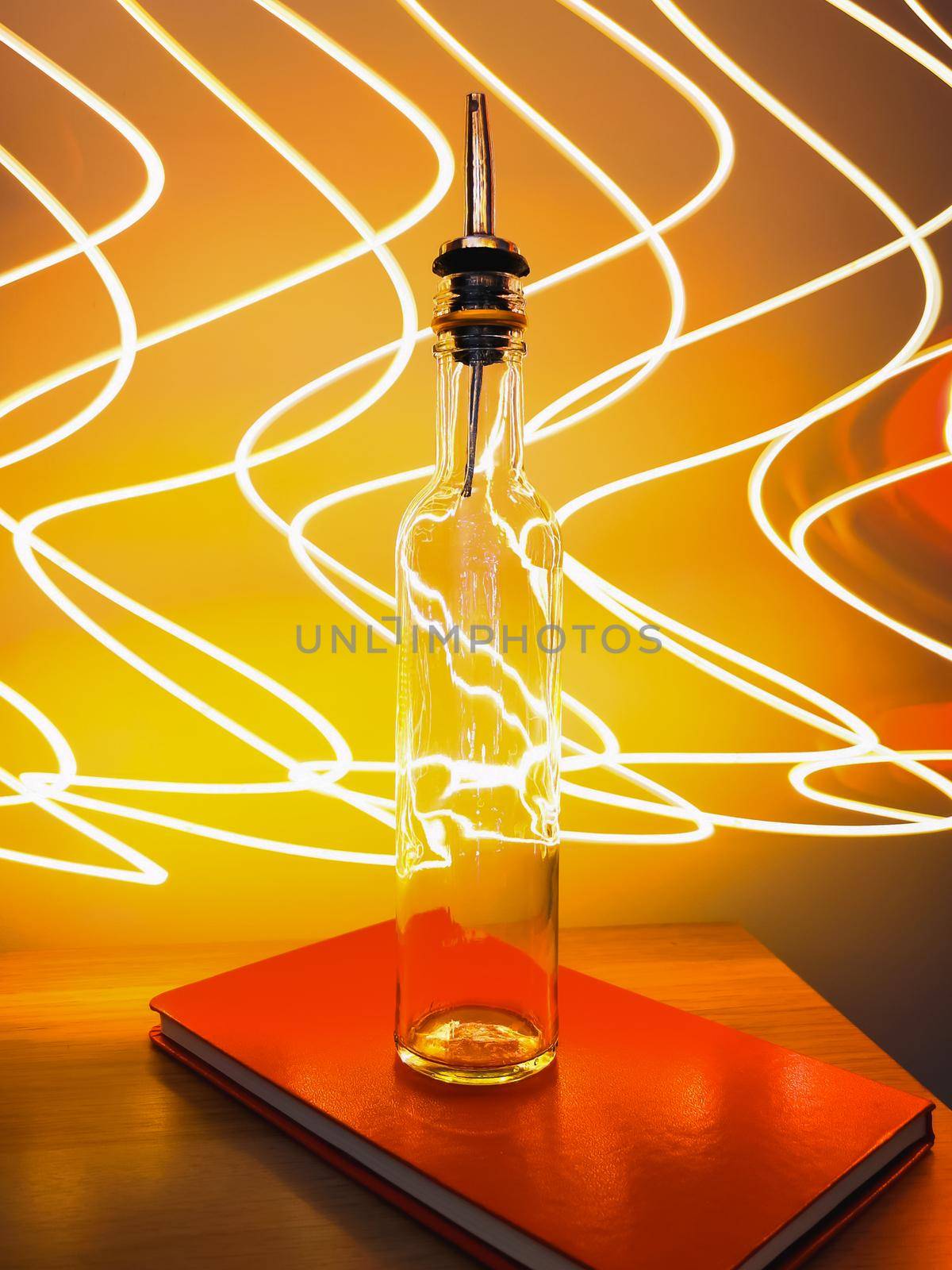 Small narrow bottle with bartender pourer on table with light paiting around