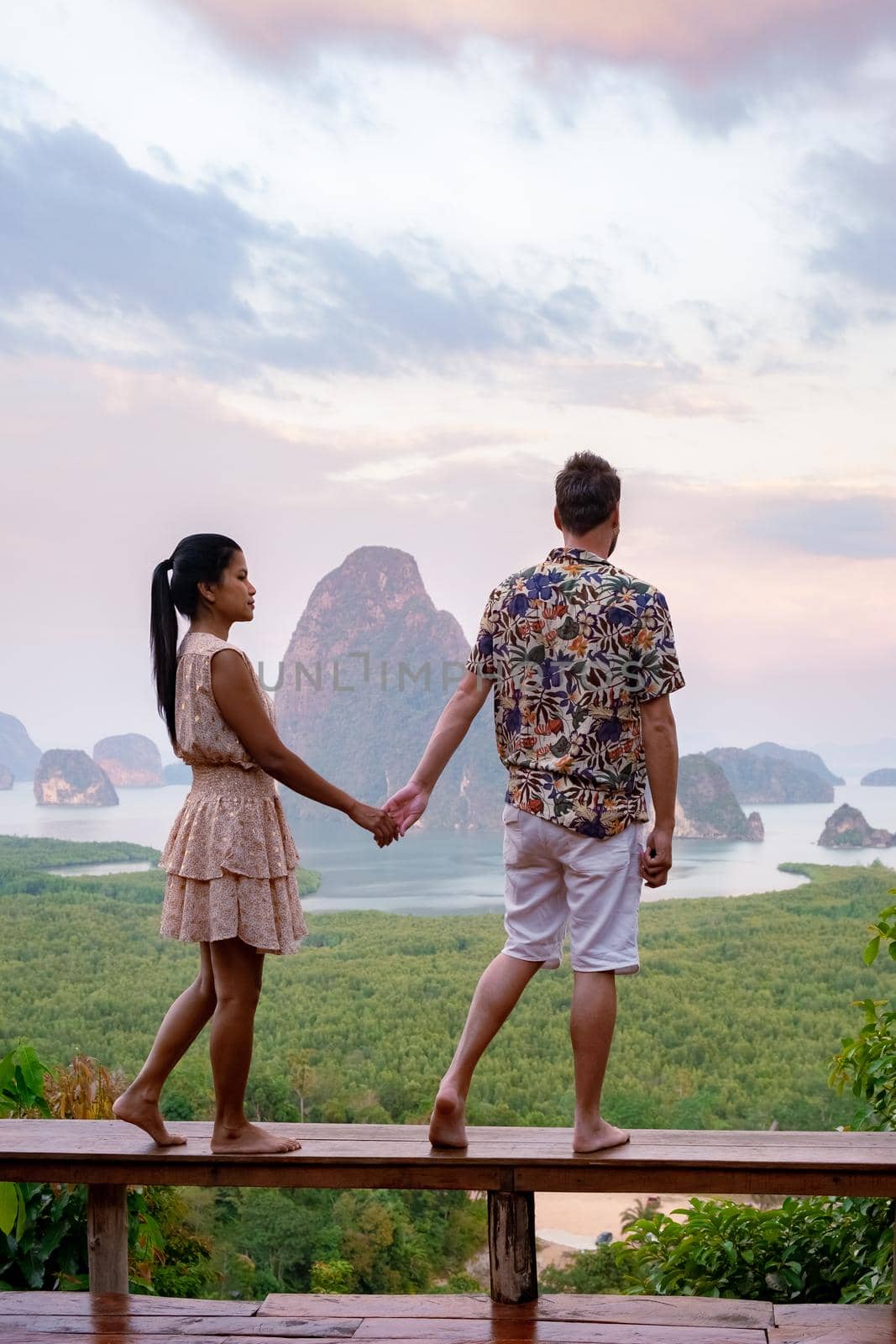couple men and woman mid age watching sunrise in Phangnga bay Thailand, Phanga bay viewpoint, couple watching sunrise on the edge of a swimming pool, infinity pool look out over Phangnga Bay Thailand by fokkebok
