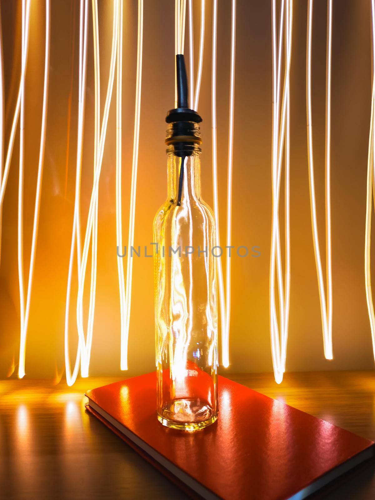 Small narrow bottle with bartender pourer on table with light paiting around