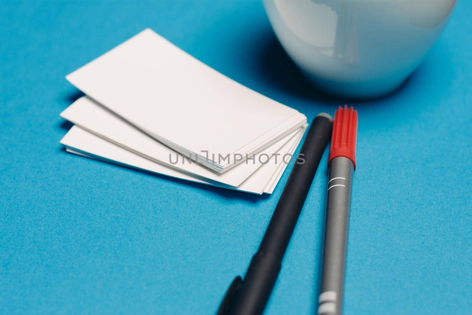business cards on blue background and pen coffee cup top view. High quality photo