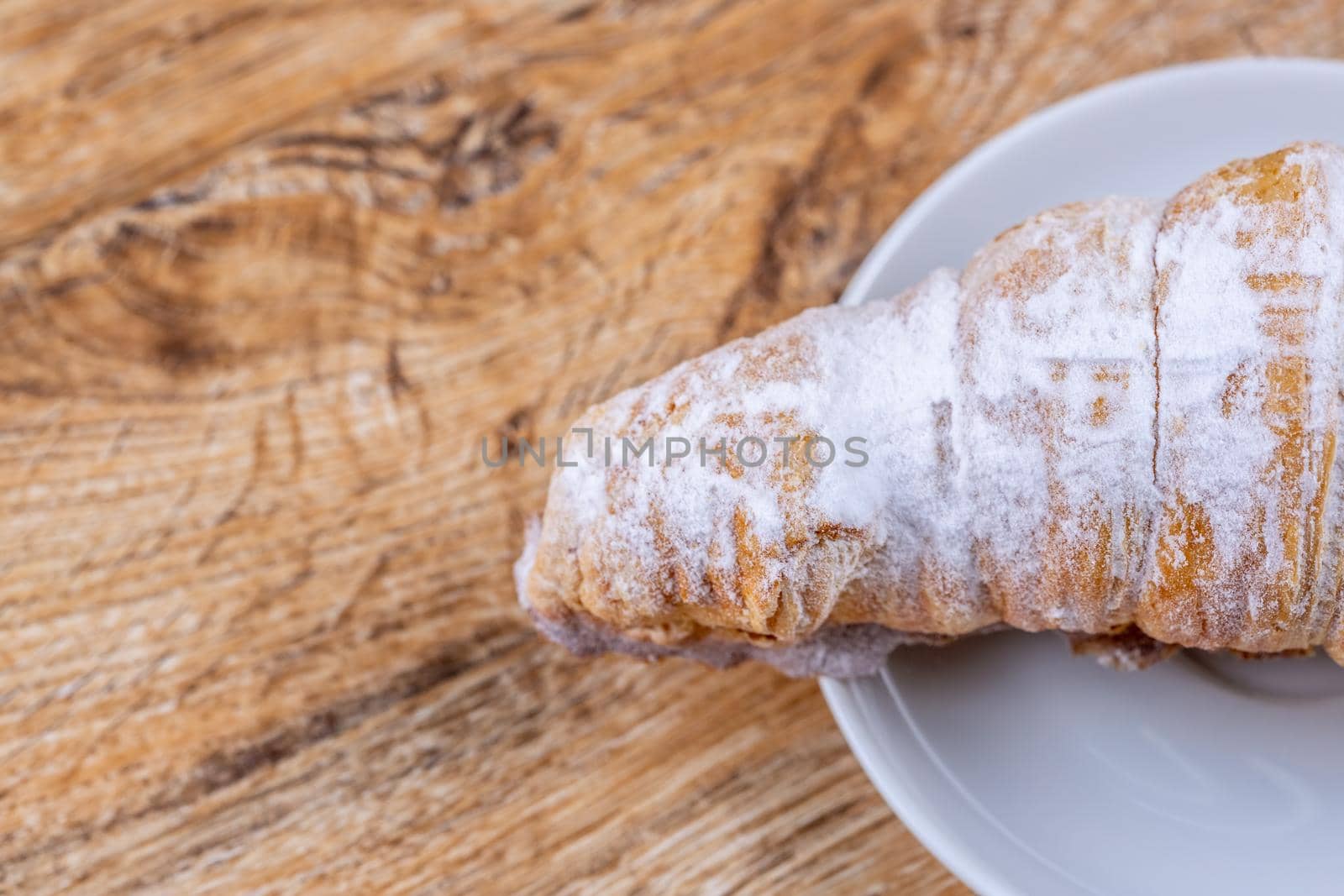 Delicious fragrant puff pastry cone with protein cream or whipped cream on white plate on wooden table